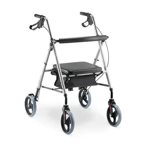 Andador ortopédico de alumínio prata com quatro rodas modelo D12 Dellamed, posicionado em ângulo diagonal sobre fundo branco. O dispositivo conta com manoplas ergonômicas pretas equipadas com manetes de freio, assento estofado preto com encosto em faixa flexível e um cesto aramado metálico preto posicionado logo abaixo do assento.