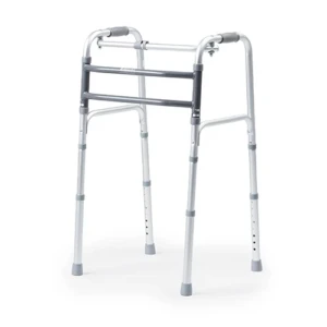 Andador ortopédico de alumínio anodizado modelo D10 Dellamed, posicionado em ângulo de três quartos sobre fundo branco. O dispositivo possui duas barras frontais estabilizadoras horizontais em tom cinza-escuro texturizado, manoplas de empunhadura superiores em borracha cinza, hastes inferiores telescópicas com furos de regulagem por pinos de clique e ponteiras de borracha cinza antiderrapantes.