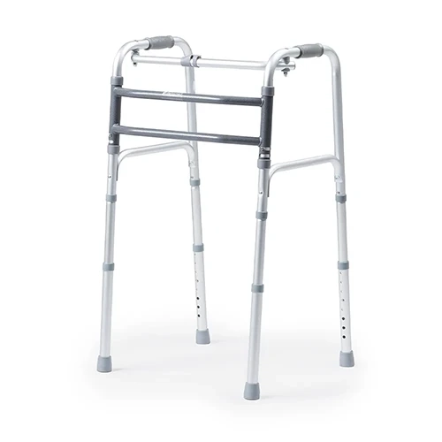 Andador ortopédico de alumínio anodizado modelo D10 Dellamed, posicionado em ângulo de três quartos sobre fundo branco. O dispositivo possui duas barras frontais estabilizadoras horizontais em tom cinza-escuro texturizado, manoplas de empunhadura superiores em borracha cinza, hastes inferiores telescópicas com furos de regulagem por pinos de clique e ponteiras de borracha cinza antiderrapantes.