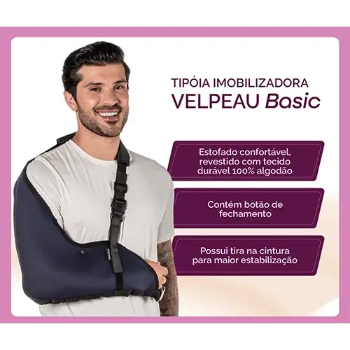 Banner publicitário digital com moldura lilás contendo a imagem de um homem sorrindo de camiseta branca que veste o modelo Tipoia Imobilizadora Velpeau Basic.webp no braço direito. O suporte ortopédico de cor azul-escura envolve completamente o antebraço e o cotovelo, subindo até cobrir a articulação do ombro. O produto possui um debrum preto nas bordas e é sustentado por uma alça preta regulável que cruza o tórax até o ombro esquerdo, equipada com fivela plástica e protetor acolchoado. À direita do modelo, sobre um fundo gradiente claro, destaca-se o título institucional "TIPÓIA IMOBILIZADORA VELPEAU Basic" em letras escuras. Logo abaixo, estão dispostos três quadros informativos horizontais roxos com cantos chanfrados contendo os textos em branco: "Estofado confortável, revestido com tecido durável 100% algodão", "Contém botão de fechamento" e "Possui tira na cintura para maior estabilização".