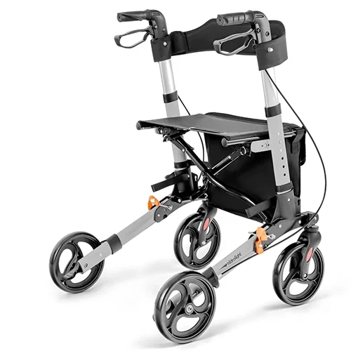 Andador ortopédico tipo rollator na cor prata e preto, equipado com quatro rodas, assento acolchoado, encosto flexível, freios de mão e cesto porta-objetos inferior.