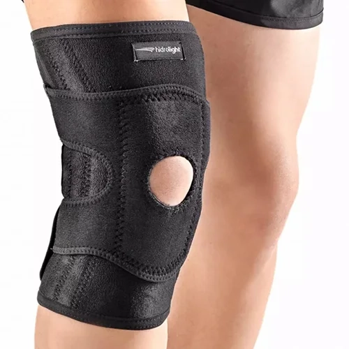 Joelheira articulada em neoprene preto de alta resistência, com orifício frontal para centralização da patela e faixas de compressão ajustáveis com fecho de contato. O equipamento oferece suporte lateral reforçado e estabilização para os ligamentos do joelho.